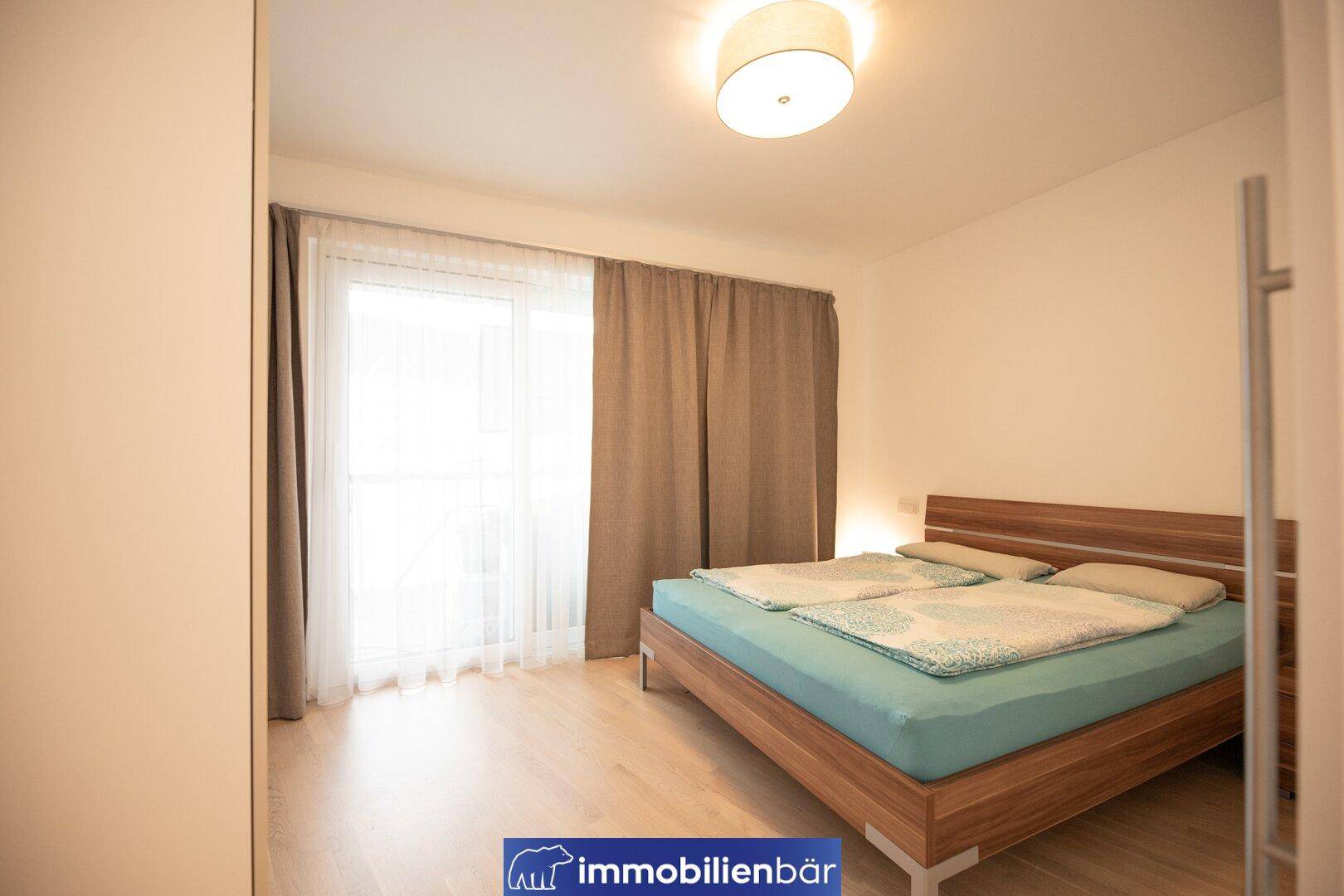 Helles Schlafzimmer mit Doppelbett und Zugang zu einem Balkon.