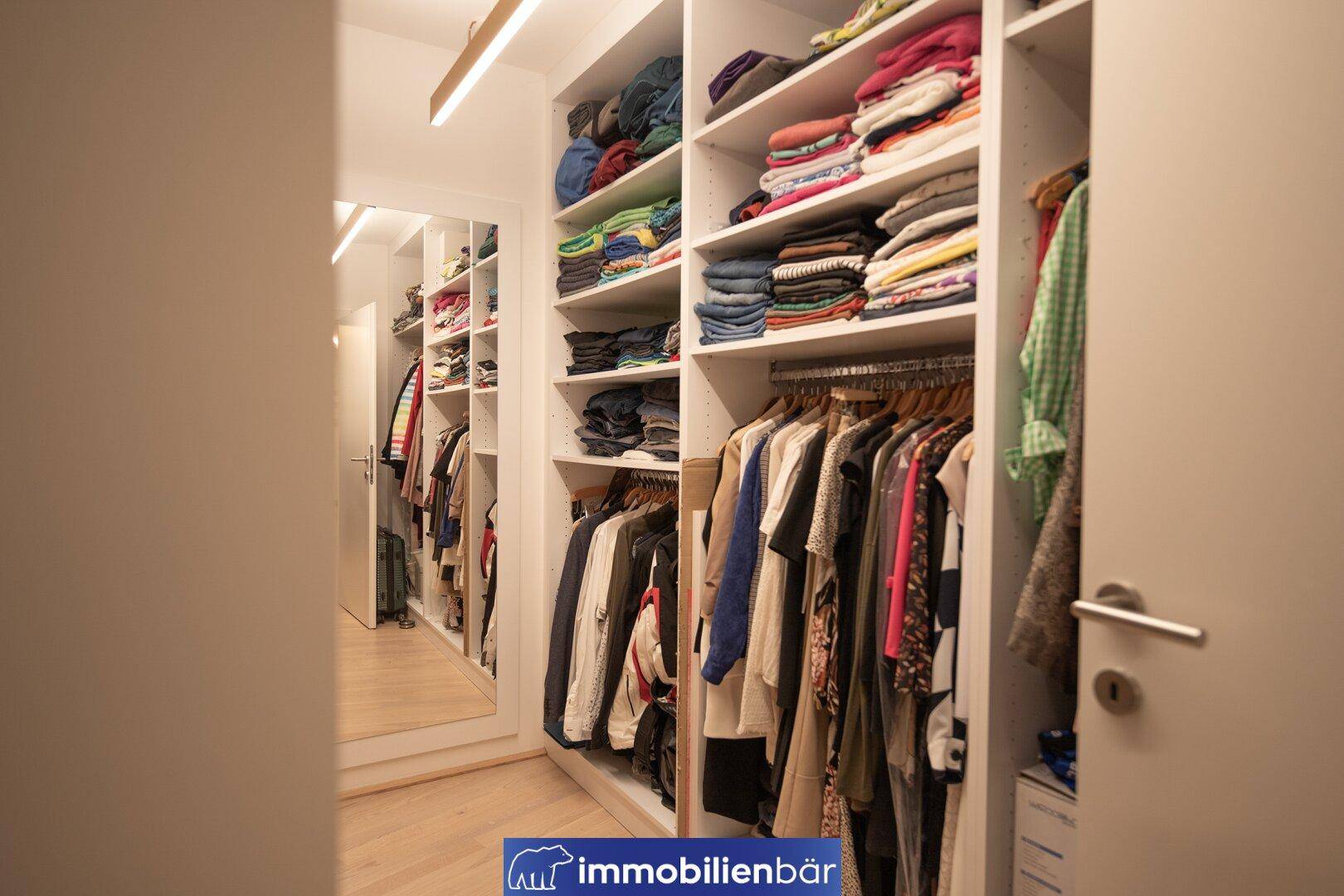 Praktischer begehbarer Kleiderschrank mit viel Stauraum und Spiegeltür.