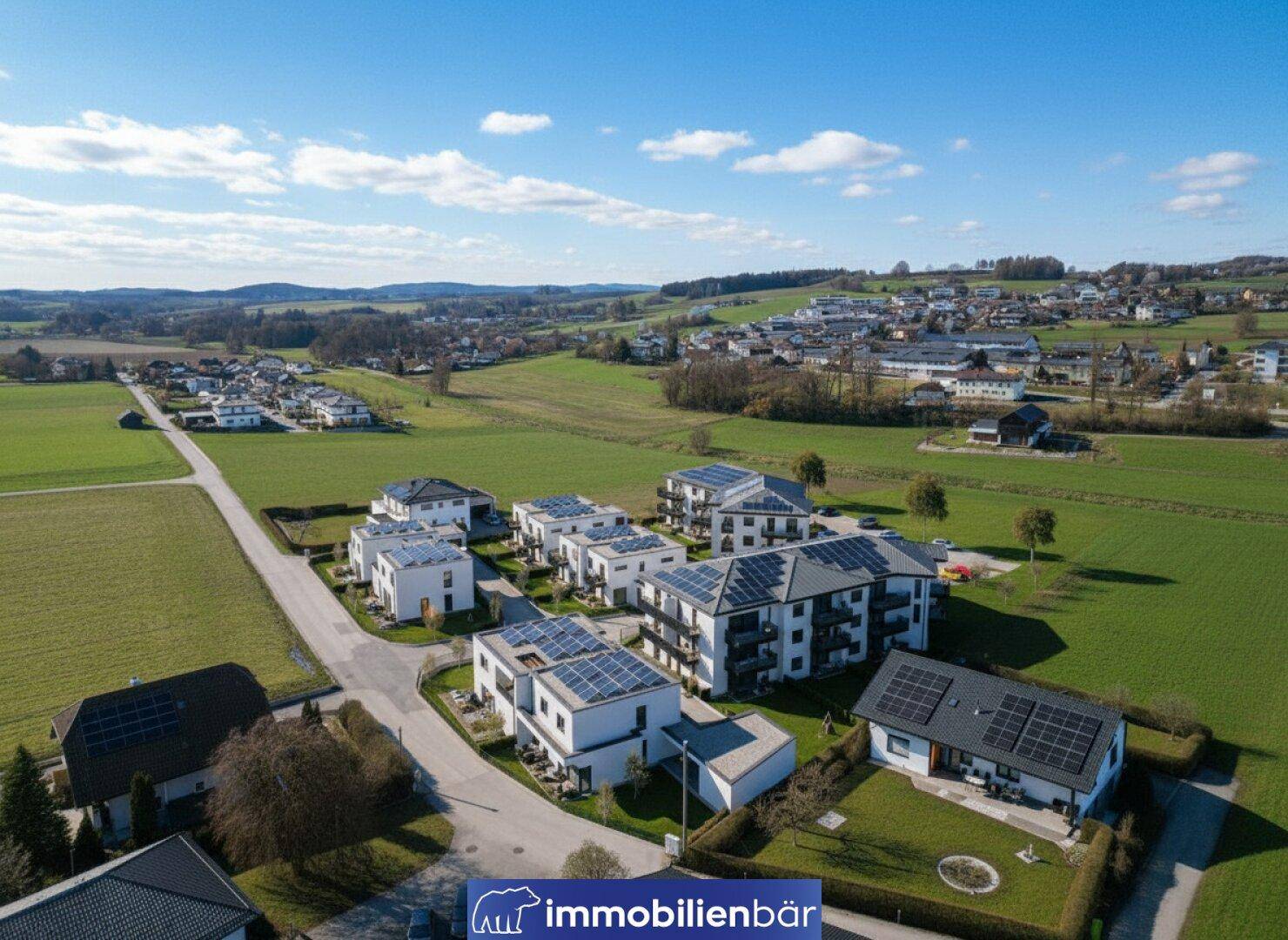Luftaufnahme einer modernen Wohnsiedlung mit Häusern und Mehrfamilienhäusern, viele davon mit Photovoltaikanlagen.