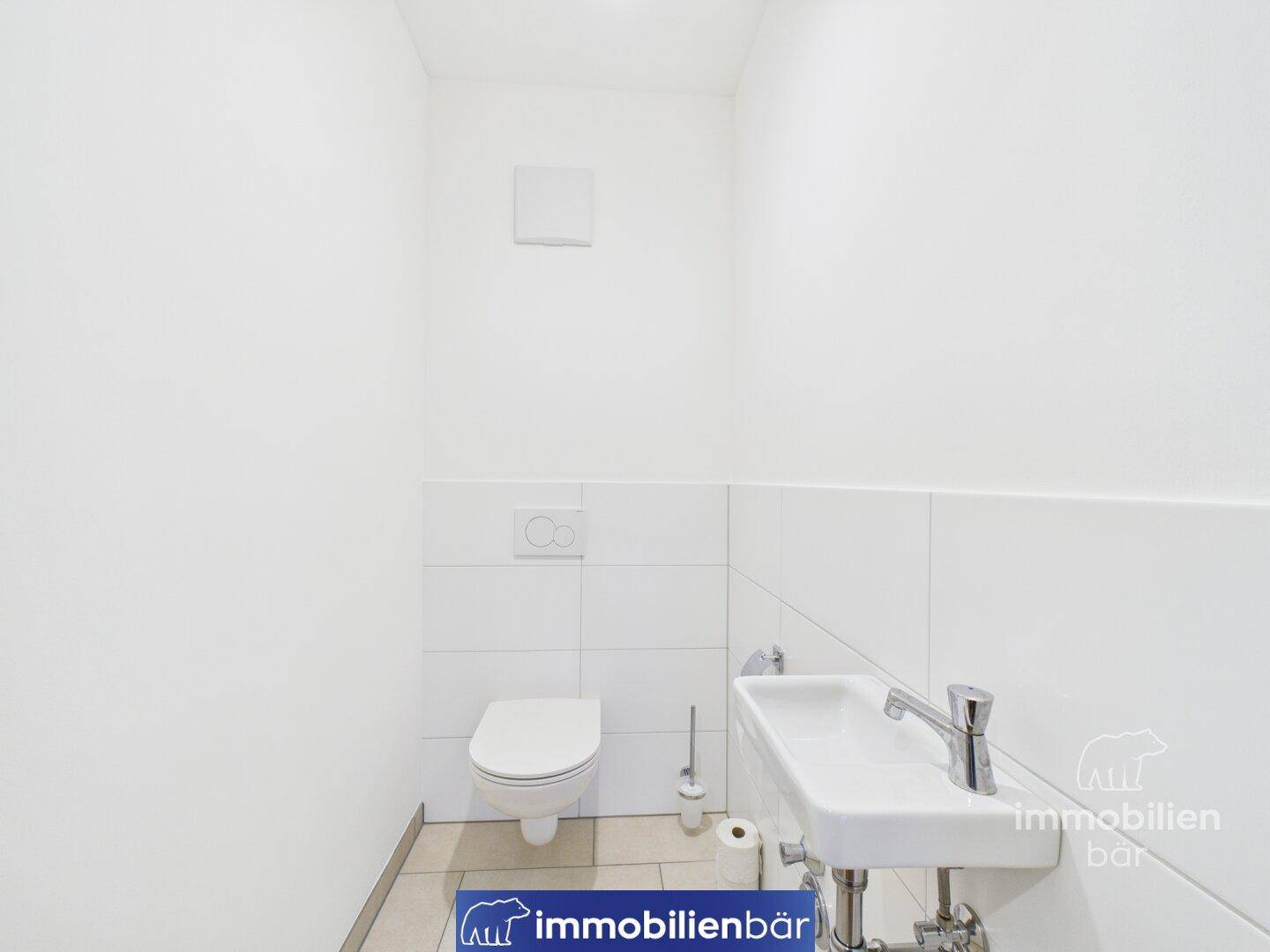 Modernes Gäste-WC mit weiß gefliesten Wänden und kleinem Waschbecken.