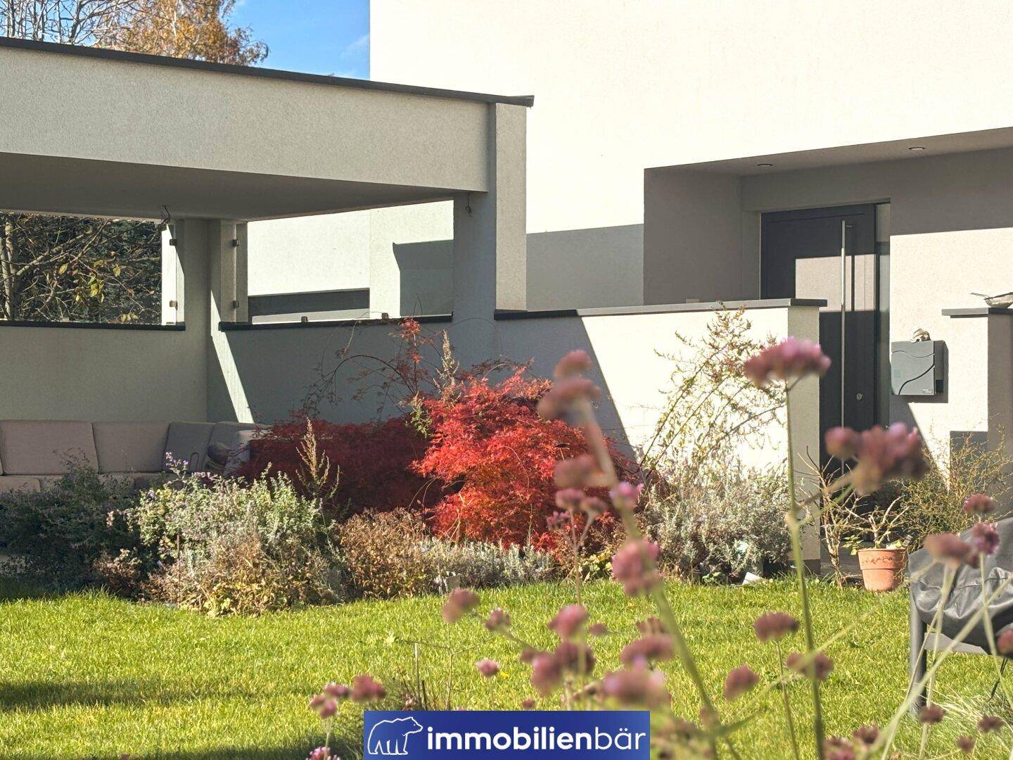 Gepflegter Garten mit Rasenfläche, Pflanzen und einer überdachten Terrasse für entspannte Stunden.