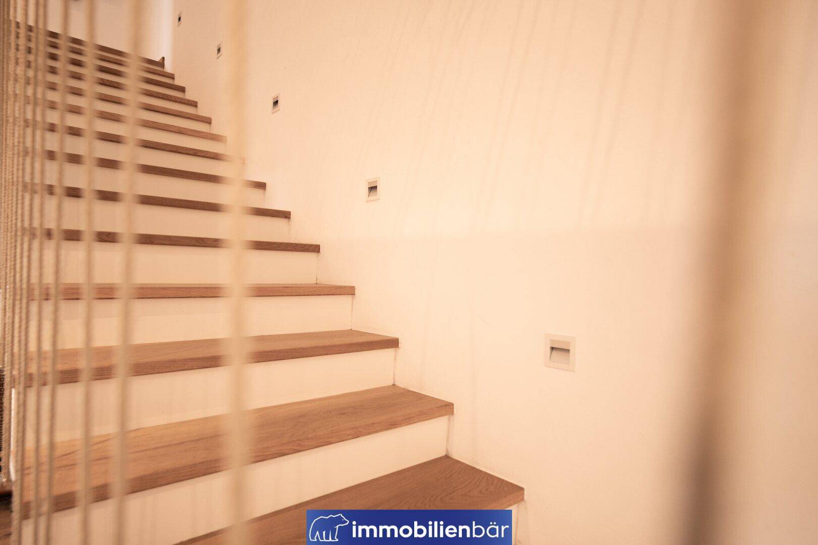 Moderne Holztreppe mit indirekter Beleuchtung, die die oberen Etagen des Hauses verbindet.