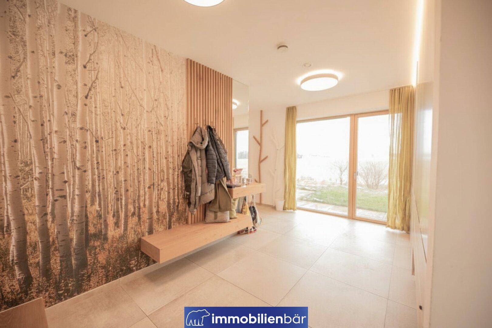 Moderner Eingangsbereich mit Holzelementen, Garderobe und einem Fenster mit Blick auf die Landschaft.