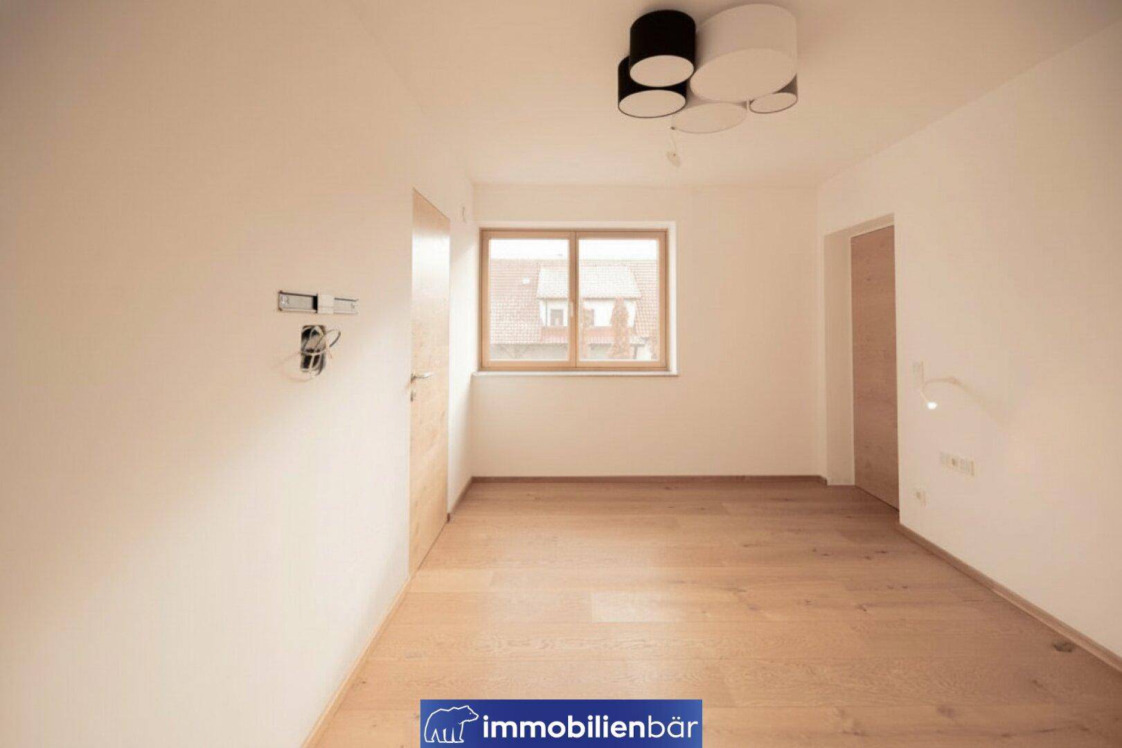 Helles, leeres Zimmer mit Holzboden und Fenster, bereit für individuelle Gestaltung.