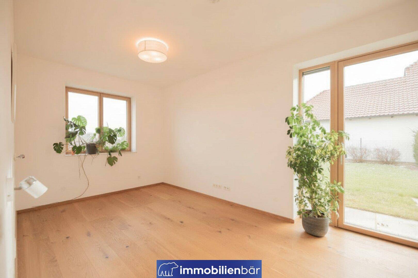 Helles Zimmer mit Holzboden und Zugang zum Garten, ideal als Schlaf- oder Arbeitszimmer.