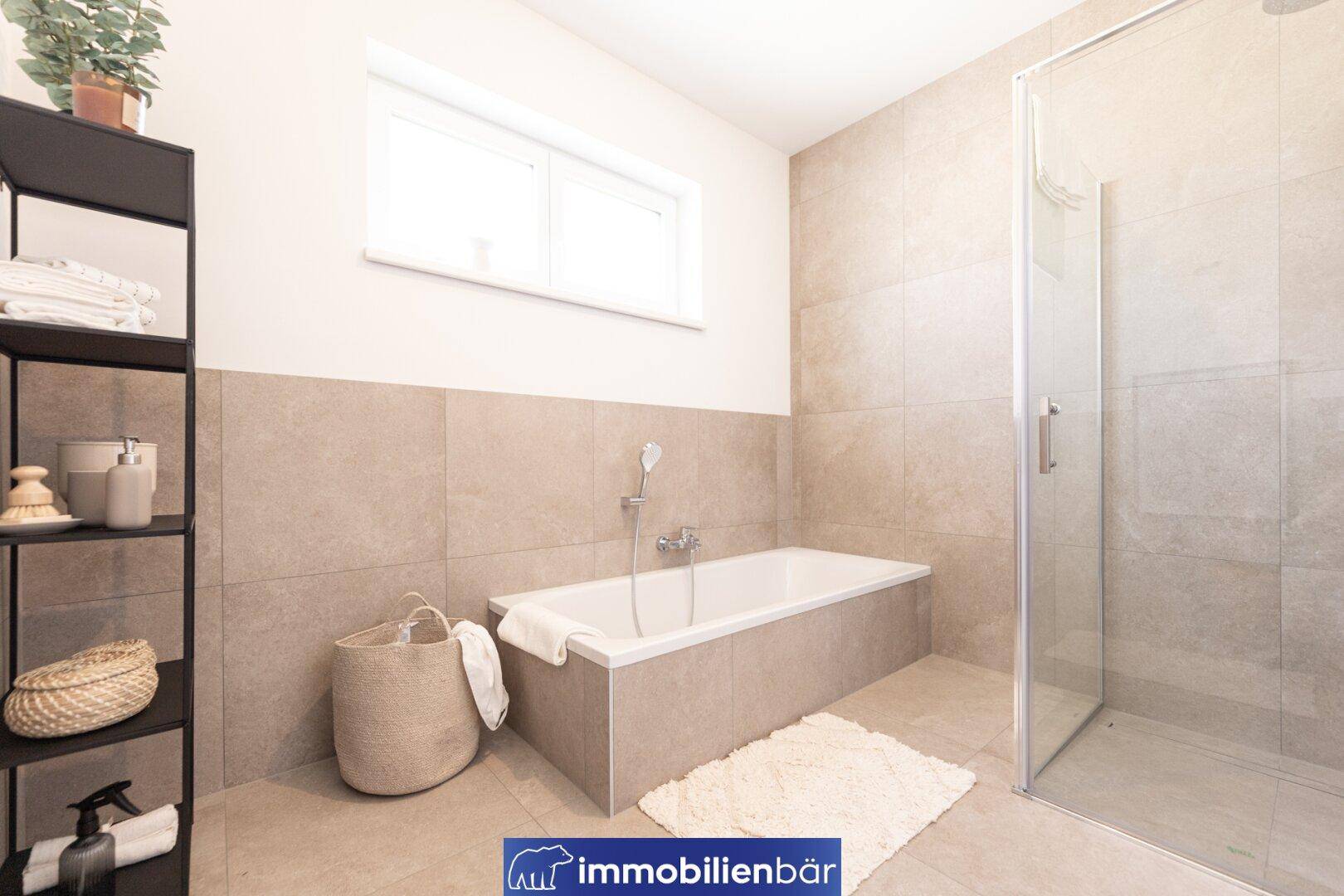 Modernes Badezimmer mit Badewanne, ebenerdiger Dusche und Fenster, in hellen Erdtönen gefliest.