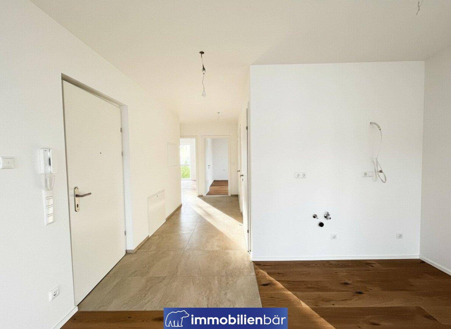 Leerer Küchenbereich mit Anschlüssen für Geräte und Fliesenboden, bereit für die Installation einer Küche.
