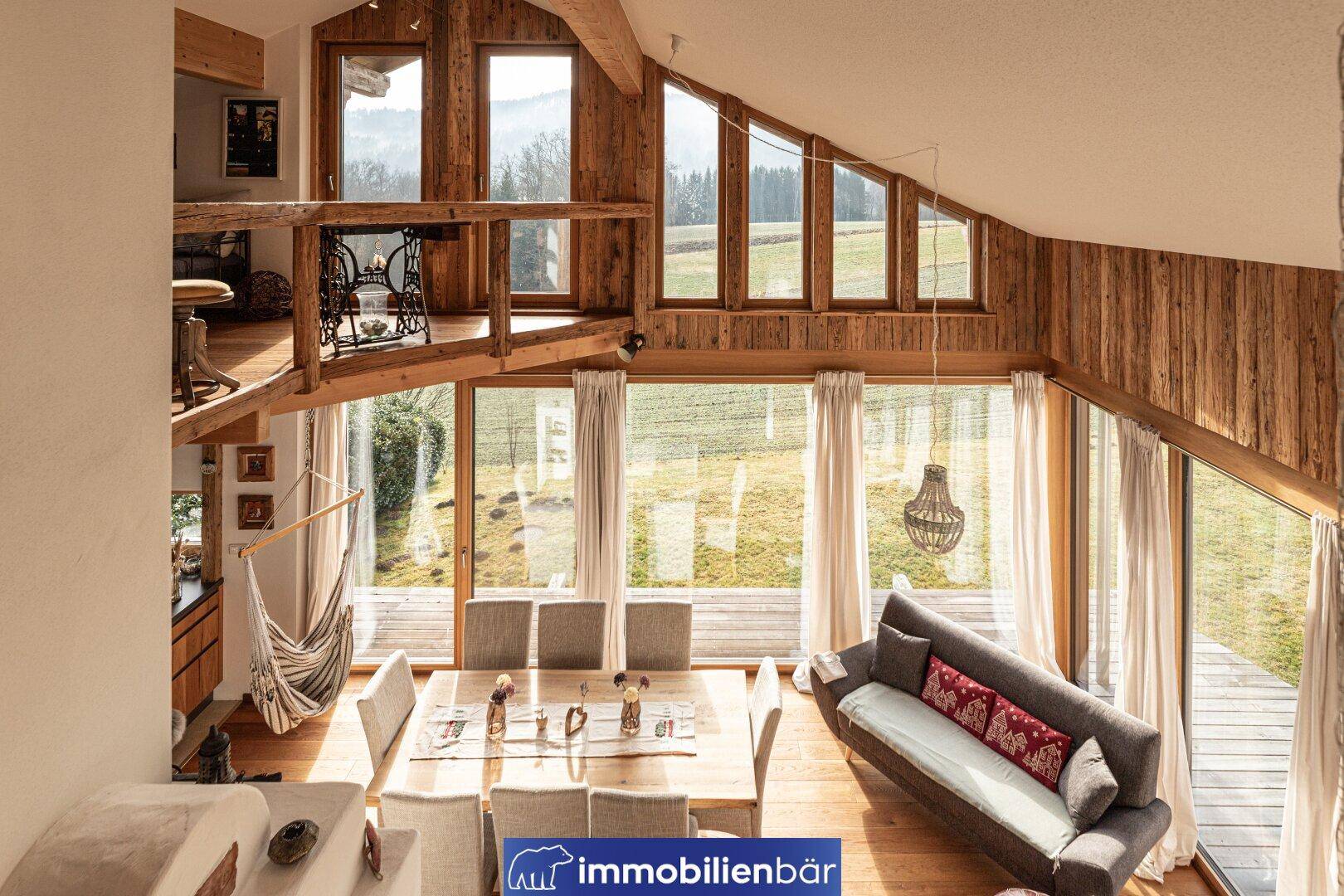 Offener Wohn-Essbereich mit hohen Decken, Holzelementen und weitem Blick in die Natur.
