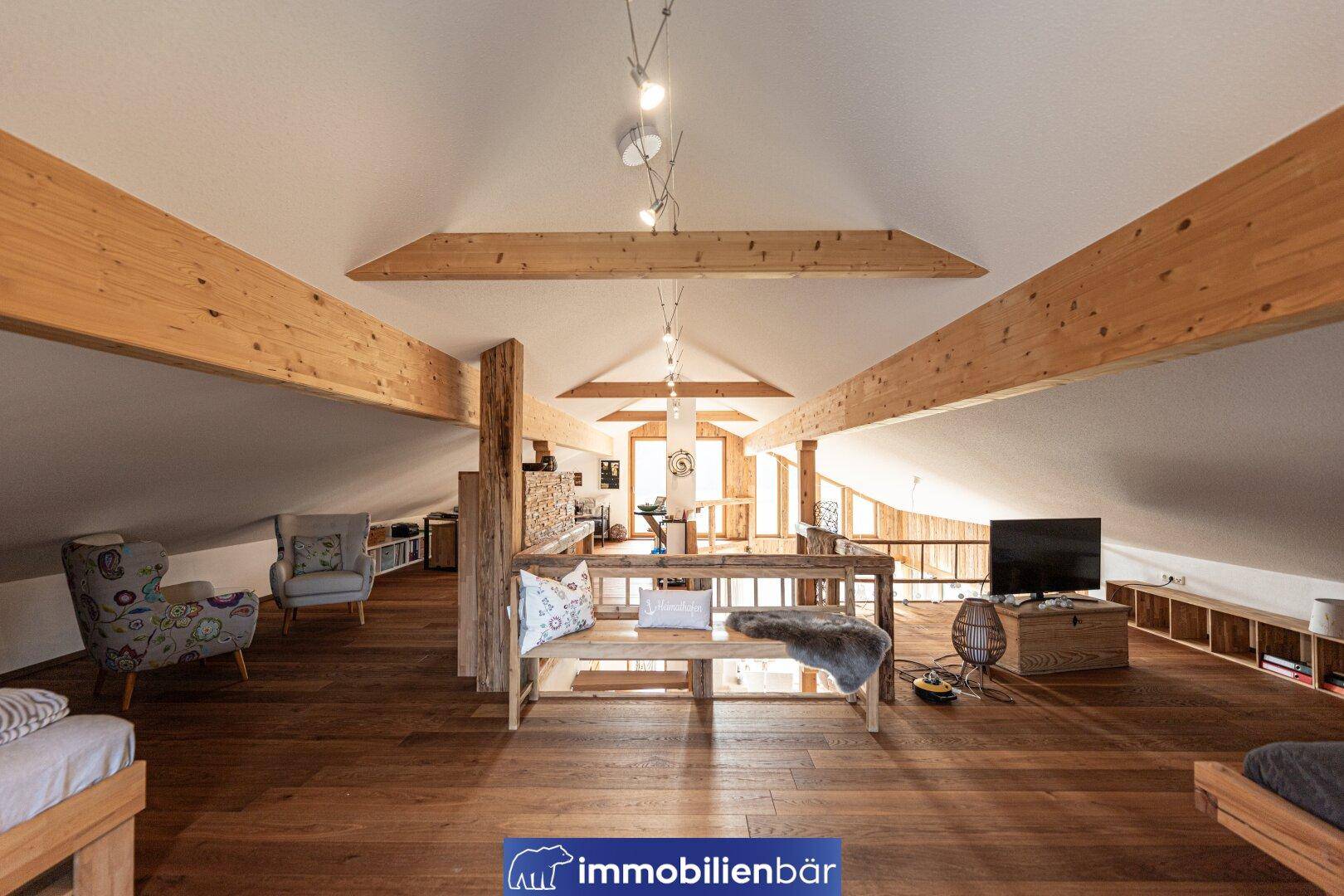Geräumige Galerie im Dachgeschoss mit Holzbalken, Holzboden und gemütlicher Sitzecke.
