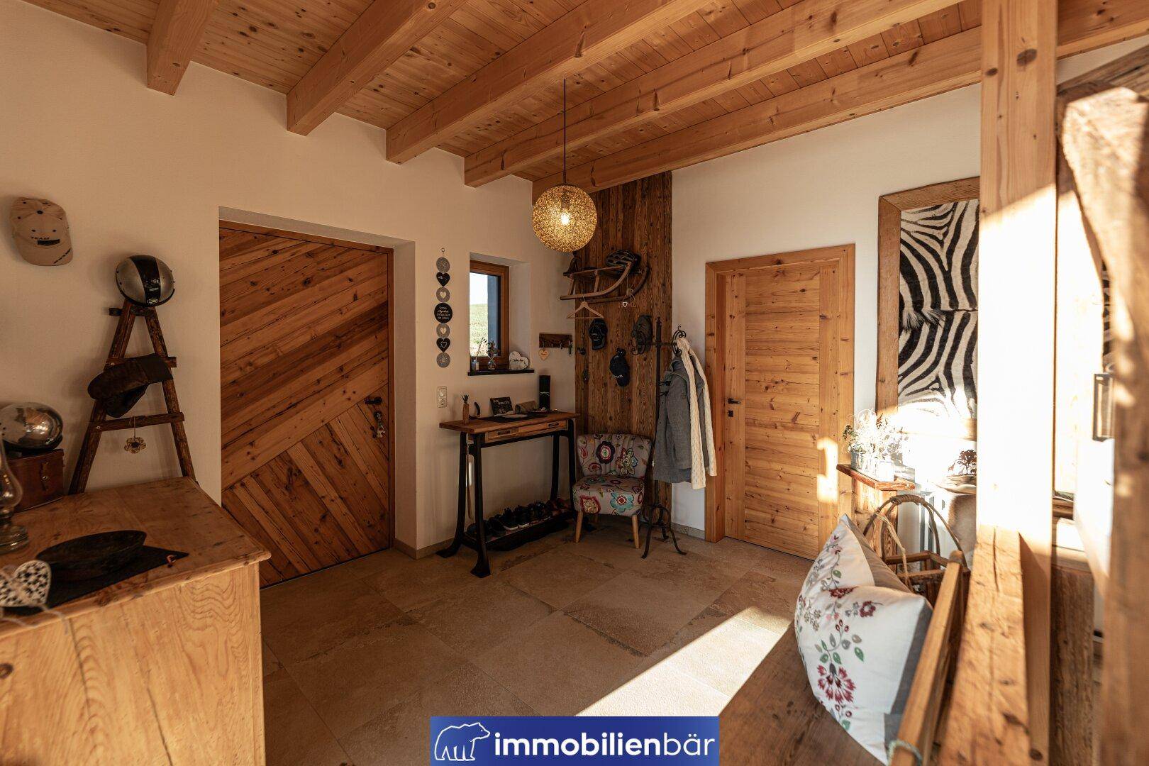 Rustikaler Eingangsbereich mit Holztüren, Holzbalkendecke und traditioneller Dekoration.