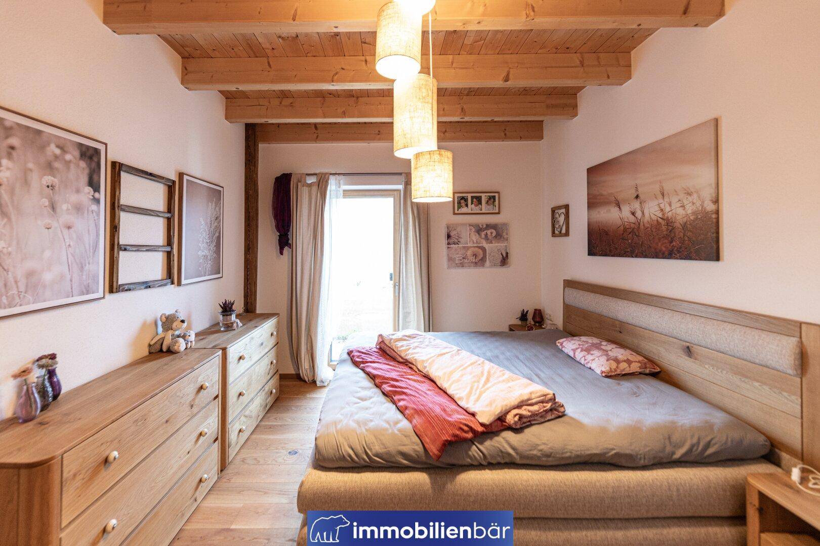Gemütliches Schlafzimmer mit Holzbalkendecke, Holzboden und Zugang zum Balkon.
