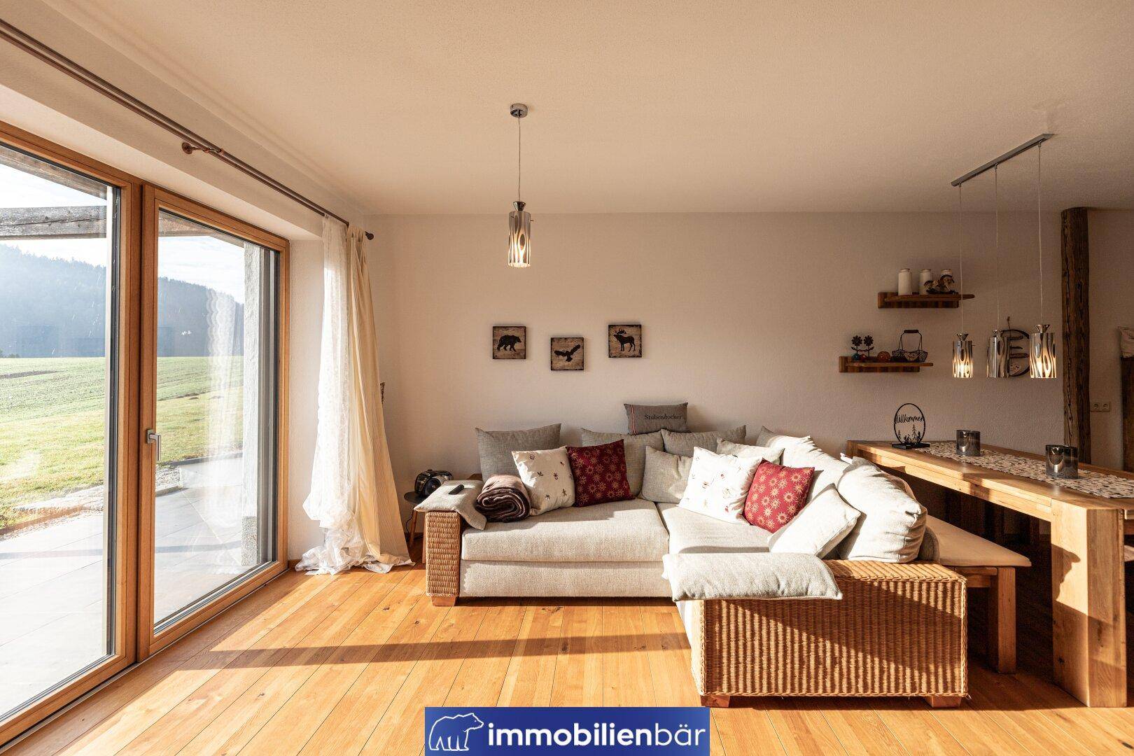 Lichtdurchflutetes Wohnzimmer mit Holzboden, bequemer Couch und Zugang zur Terrasse.