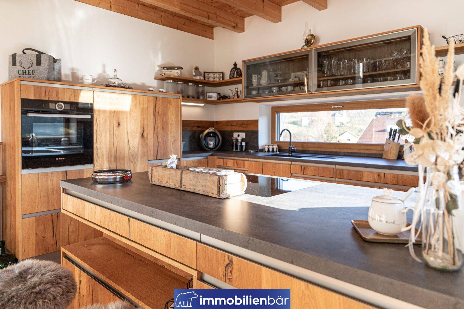 Moderne Holzküche mit integriertem Backofen, Kücheninsel und viel Arbeitsfläche.