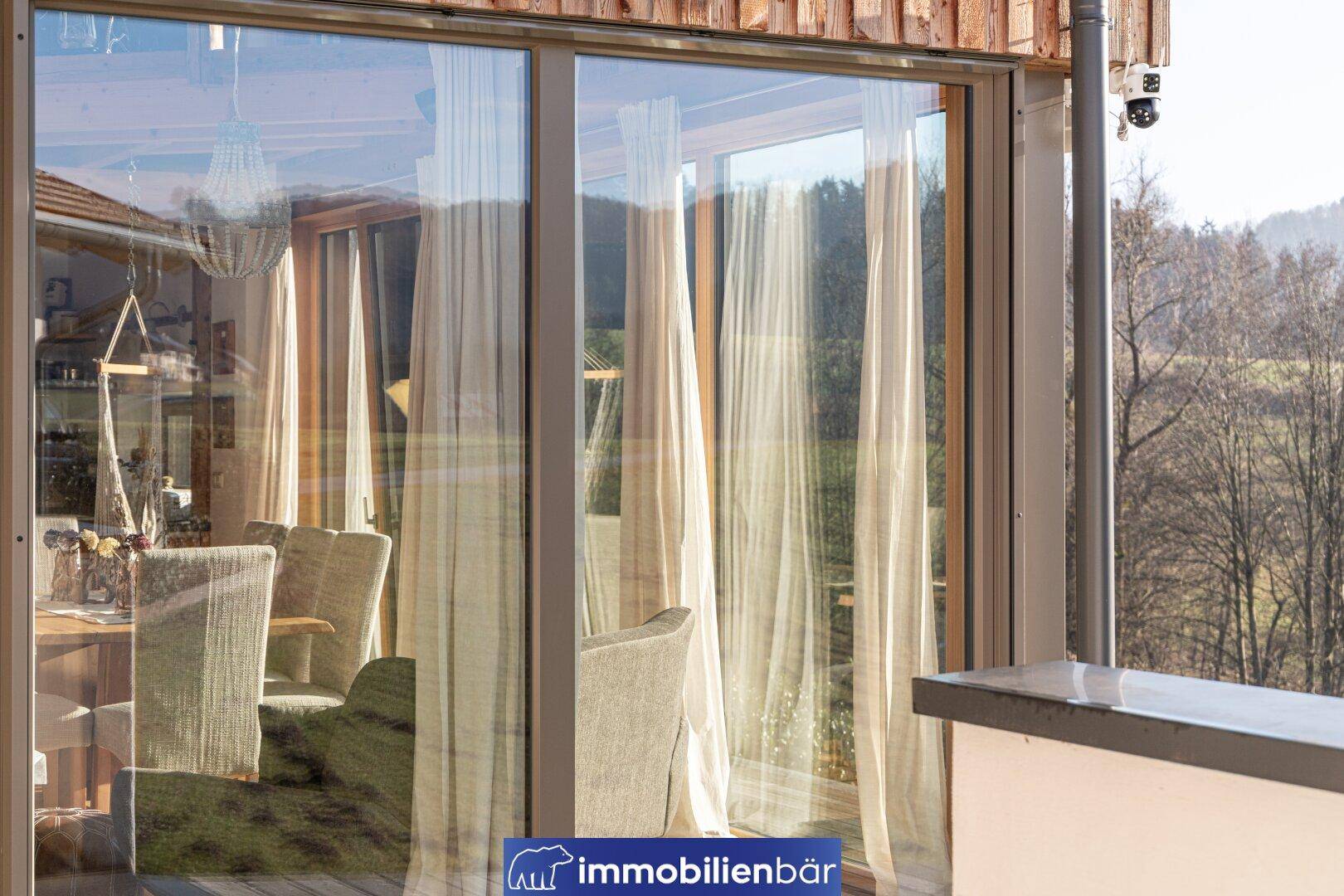 Blick vom Balkon in den hellen Wohnbereich durch große Glasfenster.
