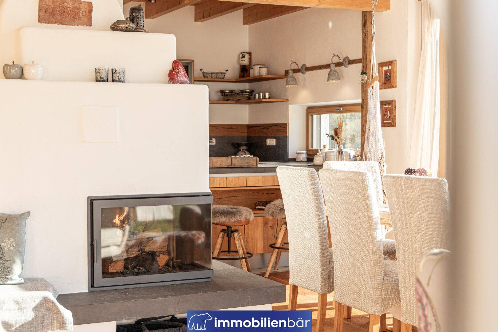 Gemütlicher Wohnbereich mit modernem Kamin, Esstisch und offener Küche im Hintergrund.