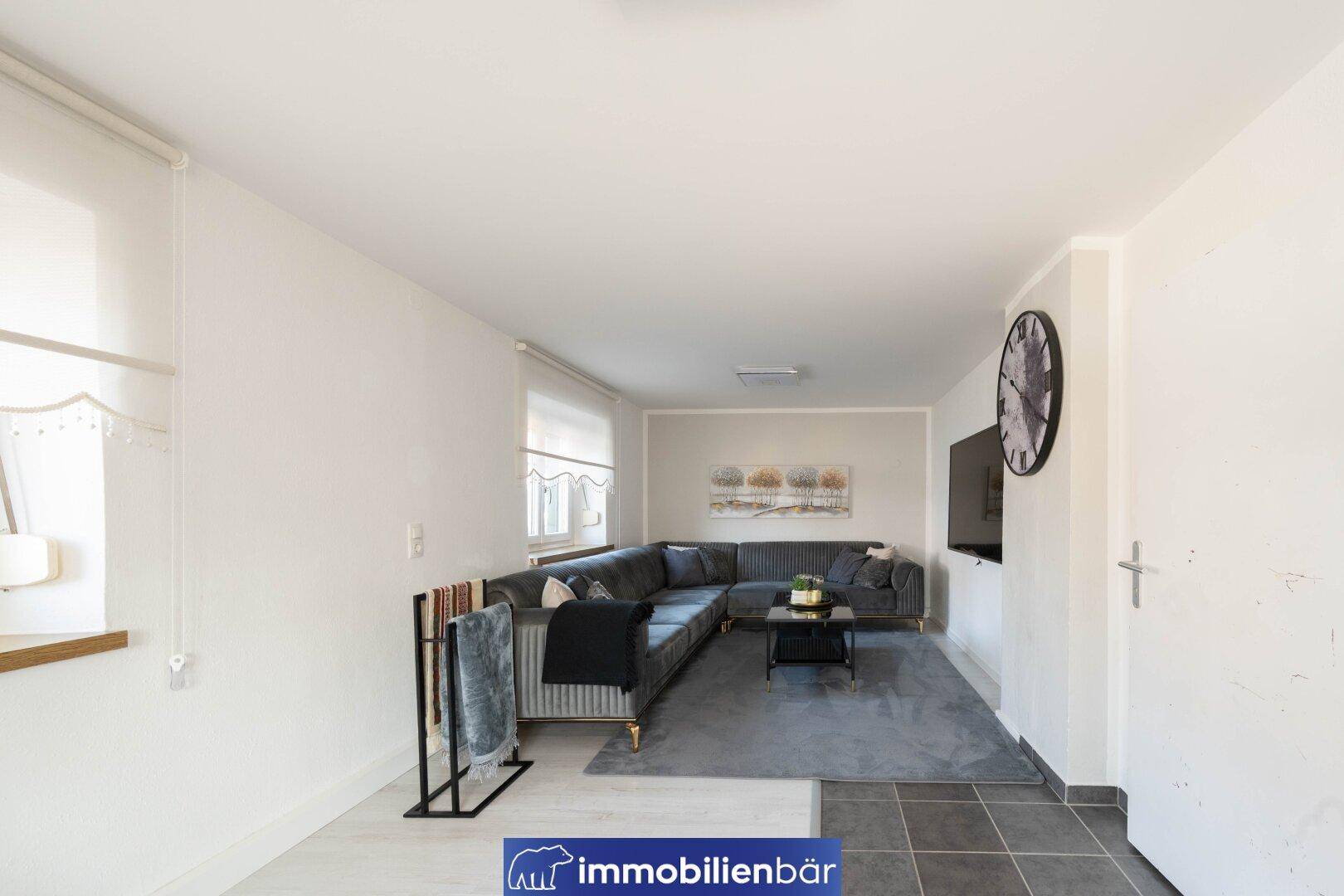 Geräumiges Wohnzimmer mit großem Ecksofa, Teppich und Fernseher an der Wand.