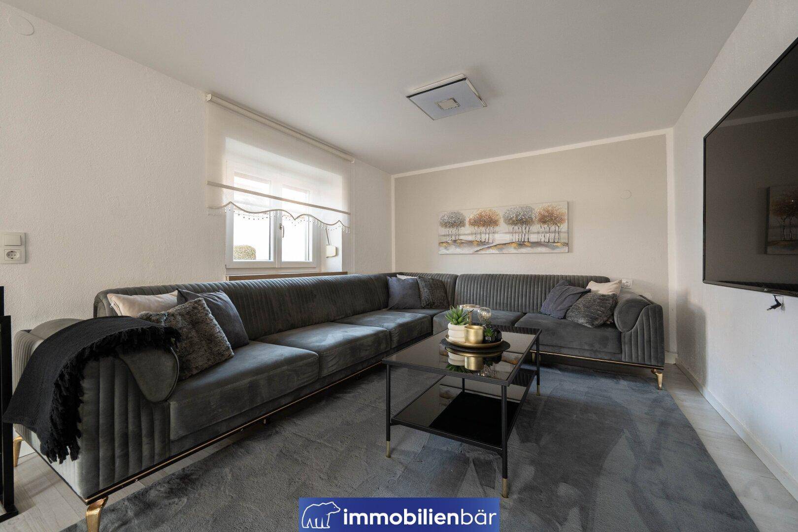 Gemütliches Wohnzimmer mit großem Ecksofa, Couchtisch und moderner Wanddekoration.