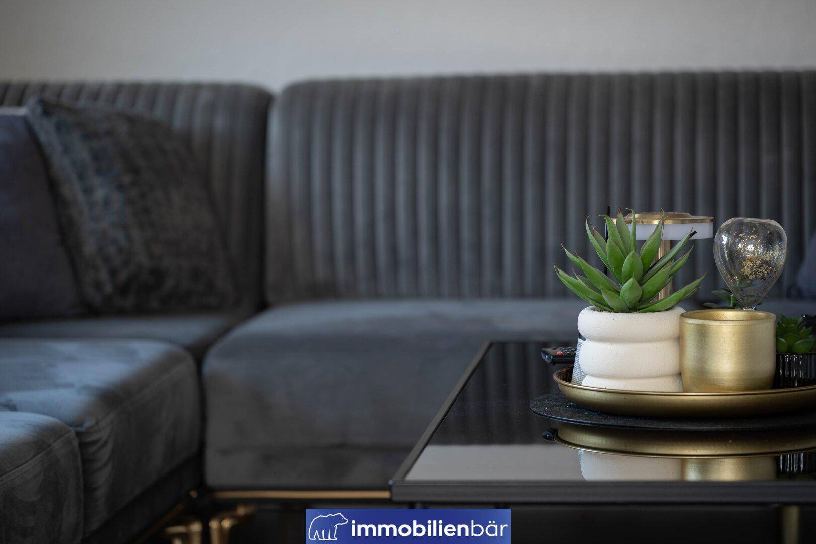 Nahaufnahme eines modernen grauen Sofas mit Dekoration auf einem Couchtisch.