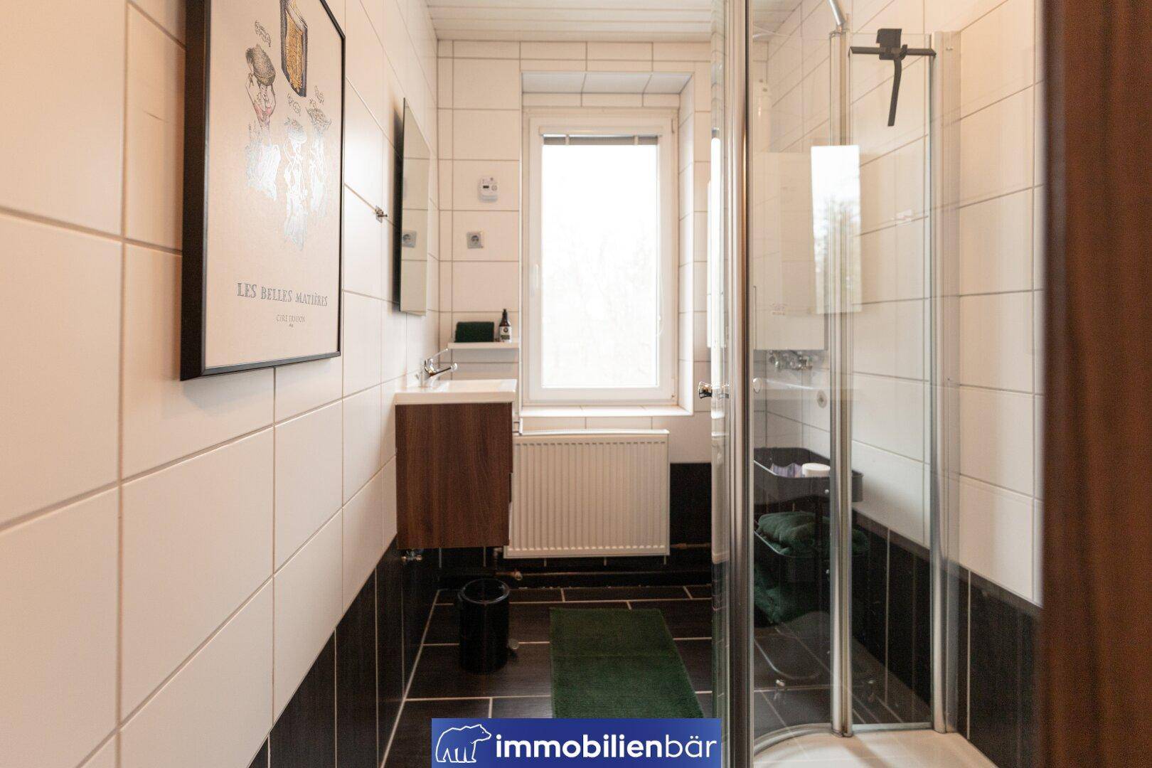 Modernes Badezimmer mit Duschkabine, Fenster und dunklen Bodenfliesen.