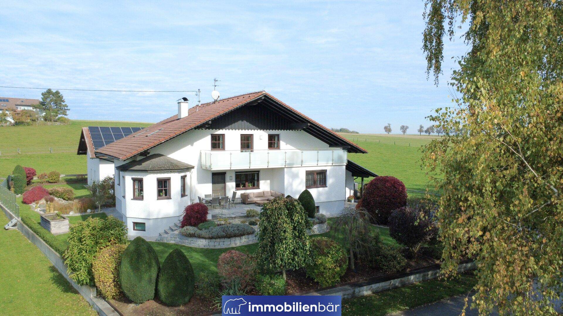 Idyllisches Haus mit gepflegtem Garten, Terrasse und Photovoltaikanlage in ländlicher Umgebung.