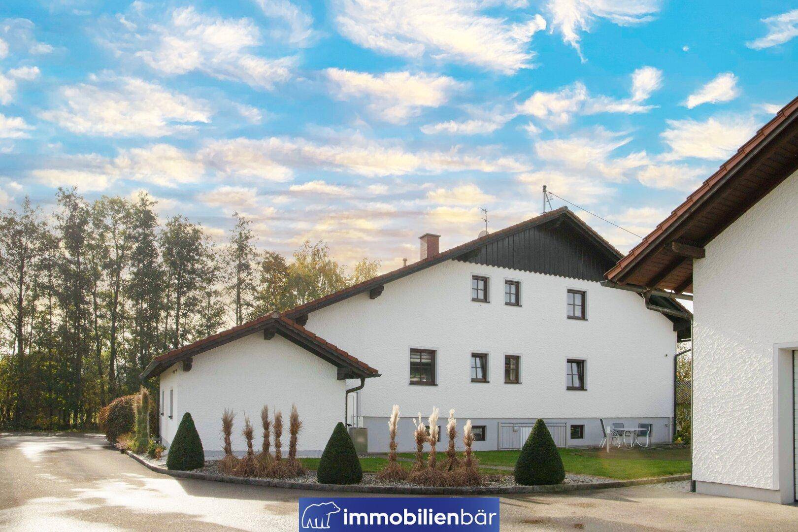 Seitenansicht des Hauses mit Zufahrt und umgebender Natur unter einem weiten Himmel.
