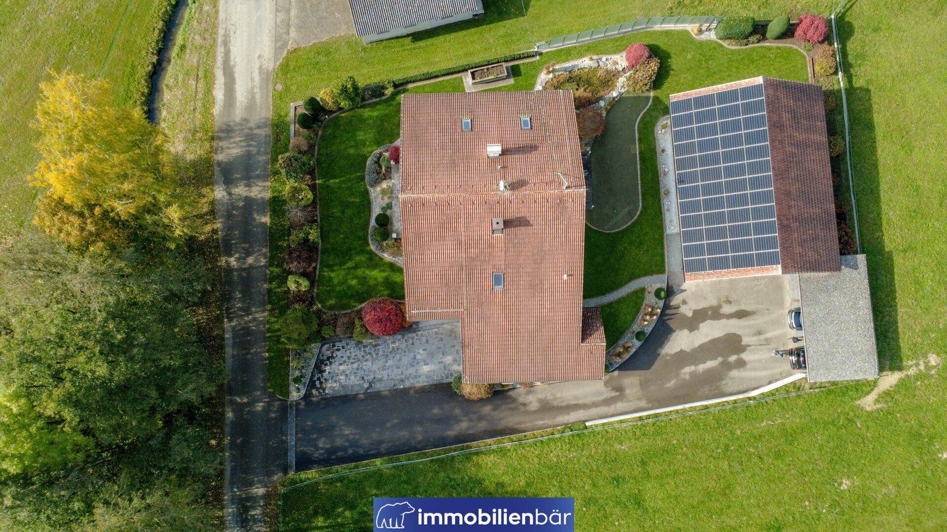 Luftaufnahme des Anwesens mit Haus, Garten, Photovoltaikanlage und weitläufiger Zufahrt.