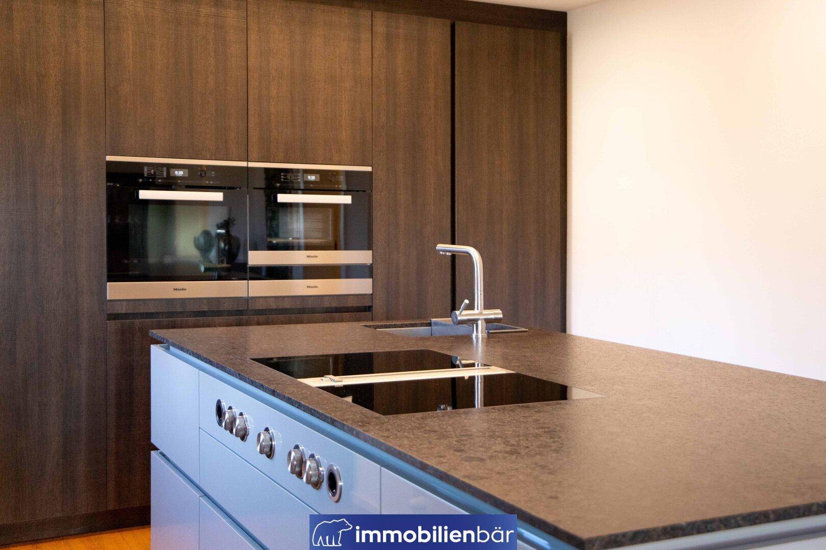 Moderne Küche mit Kochinsel, Induktionskochfeld und hochwertigen Miele Einbaugeräten.