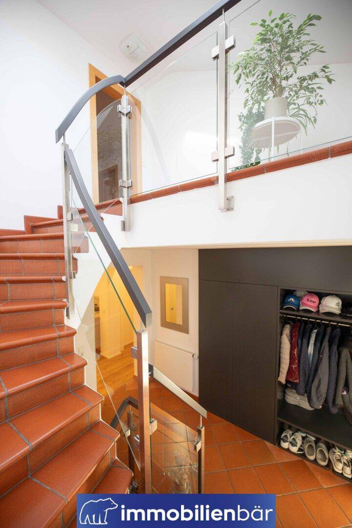 Heller Treppenaufgang mit Glasgeländer und integriertem Stauraum, funktional und modern.