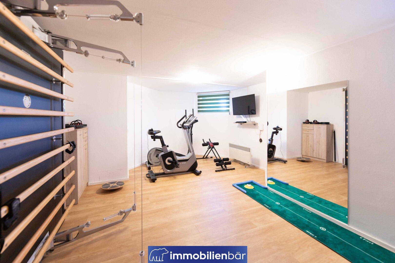 Gut ausgestatteter Fitnessraum mit verschiedenen Trainingsgeräten und Spiegeln für Sportaktivitäten.