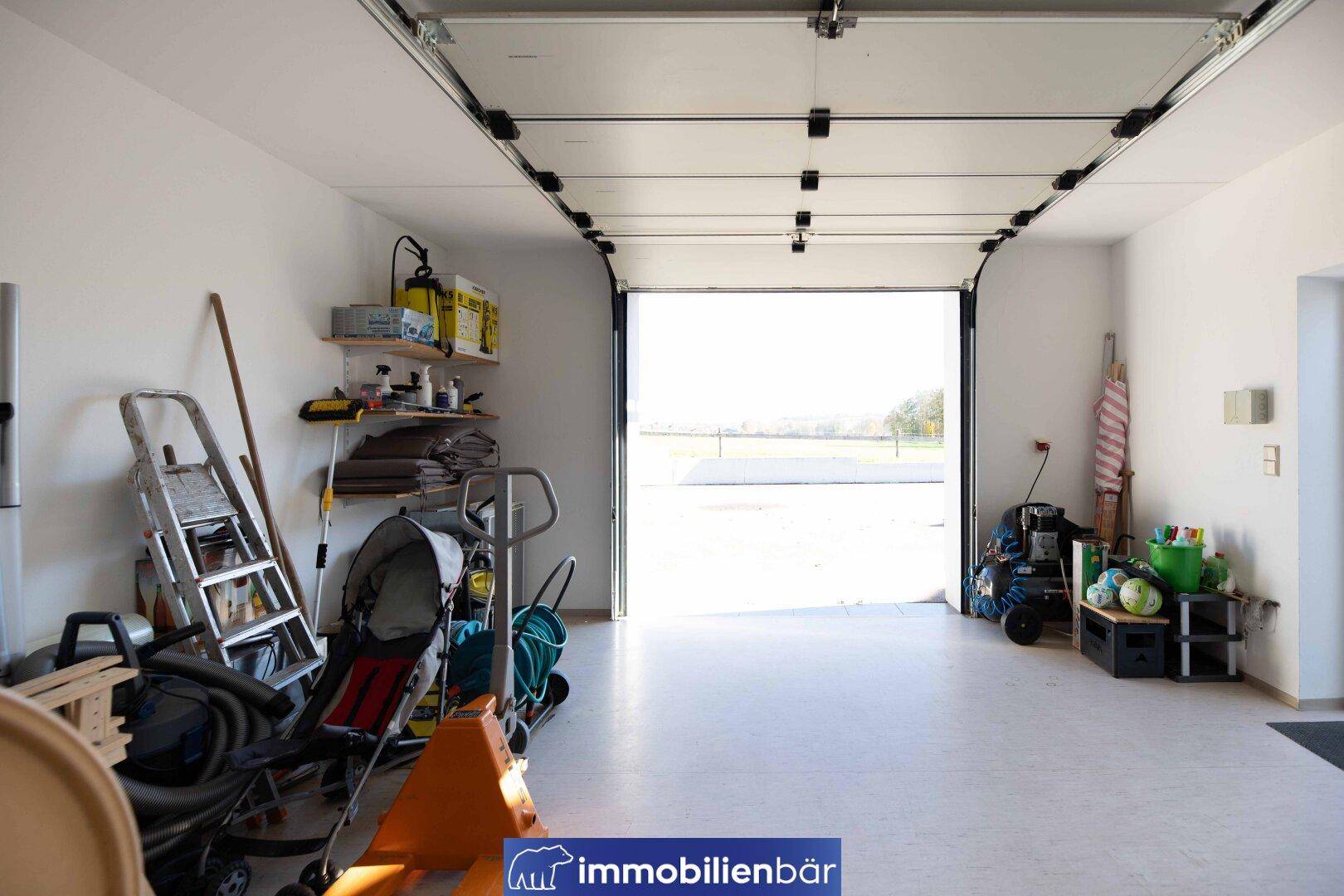 Geräumige Garage mit Rolltor und ausreichend Stauraum für Fahrzeuge und Gartengeräte.