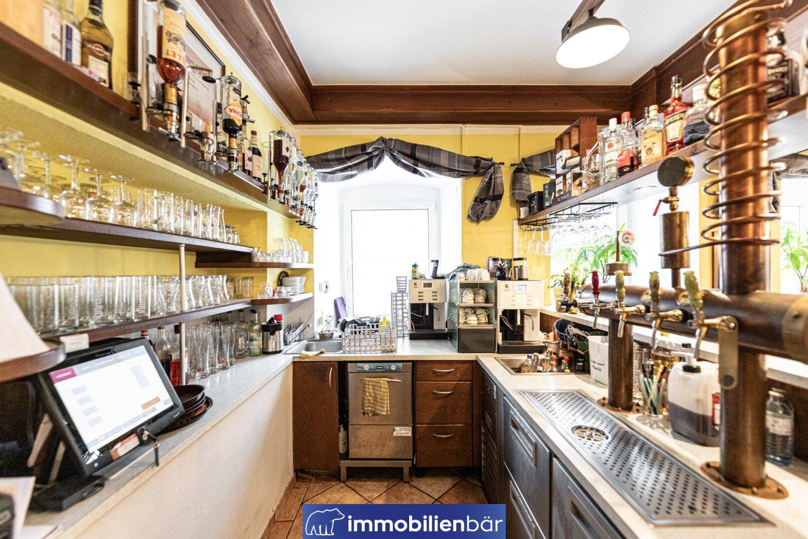Voll ausgestattete Bar mit professionellen Geräten, vielen Gläsern und Flaschen.