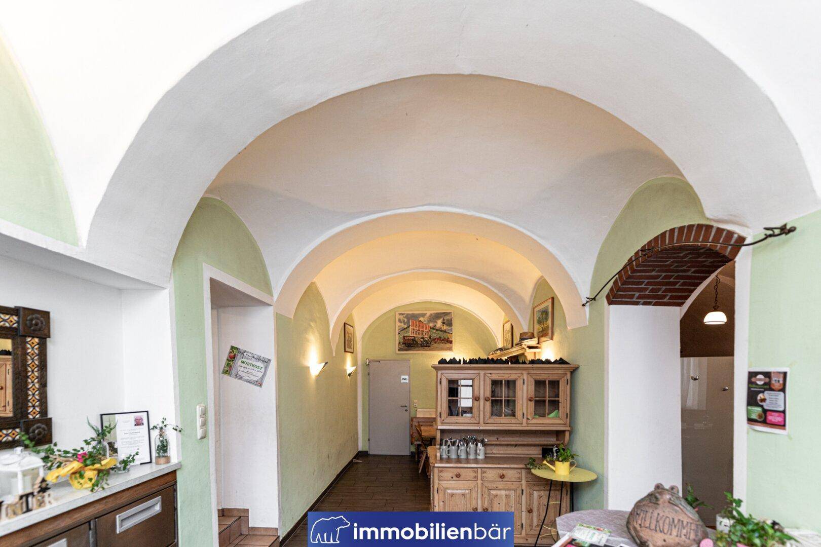 Heller Flur mit mehreren Gewölbebögen und traditionellem Holzschrank, der zu weiteren Räumen führt.