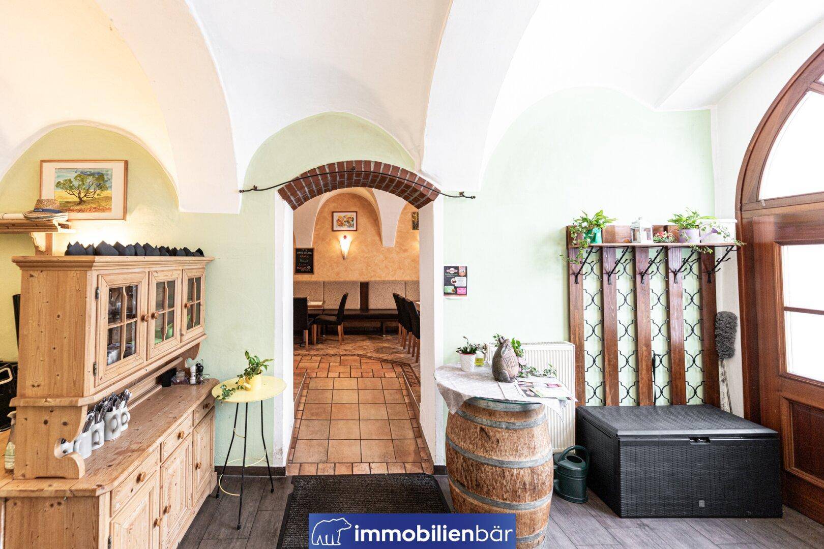 Einladender Eingangsbereich mit Holzboden, traditionellem Schrank und dekorativem Weinfass.