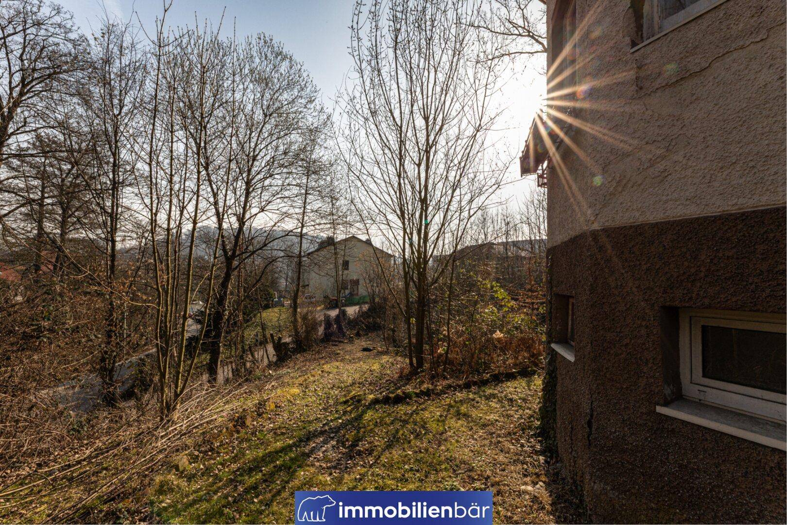 Seitenansicht des Hauses mit Blick auf die umliegende Landschaft und kahle Bäume.