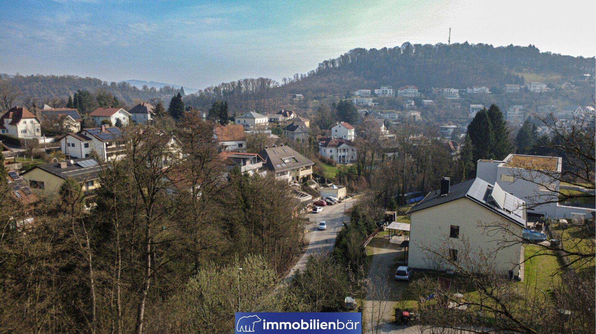 Weitläufiger Blick auf eine Wohngegend mit Häusern und einer Straße, umgeben von Natur.