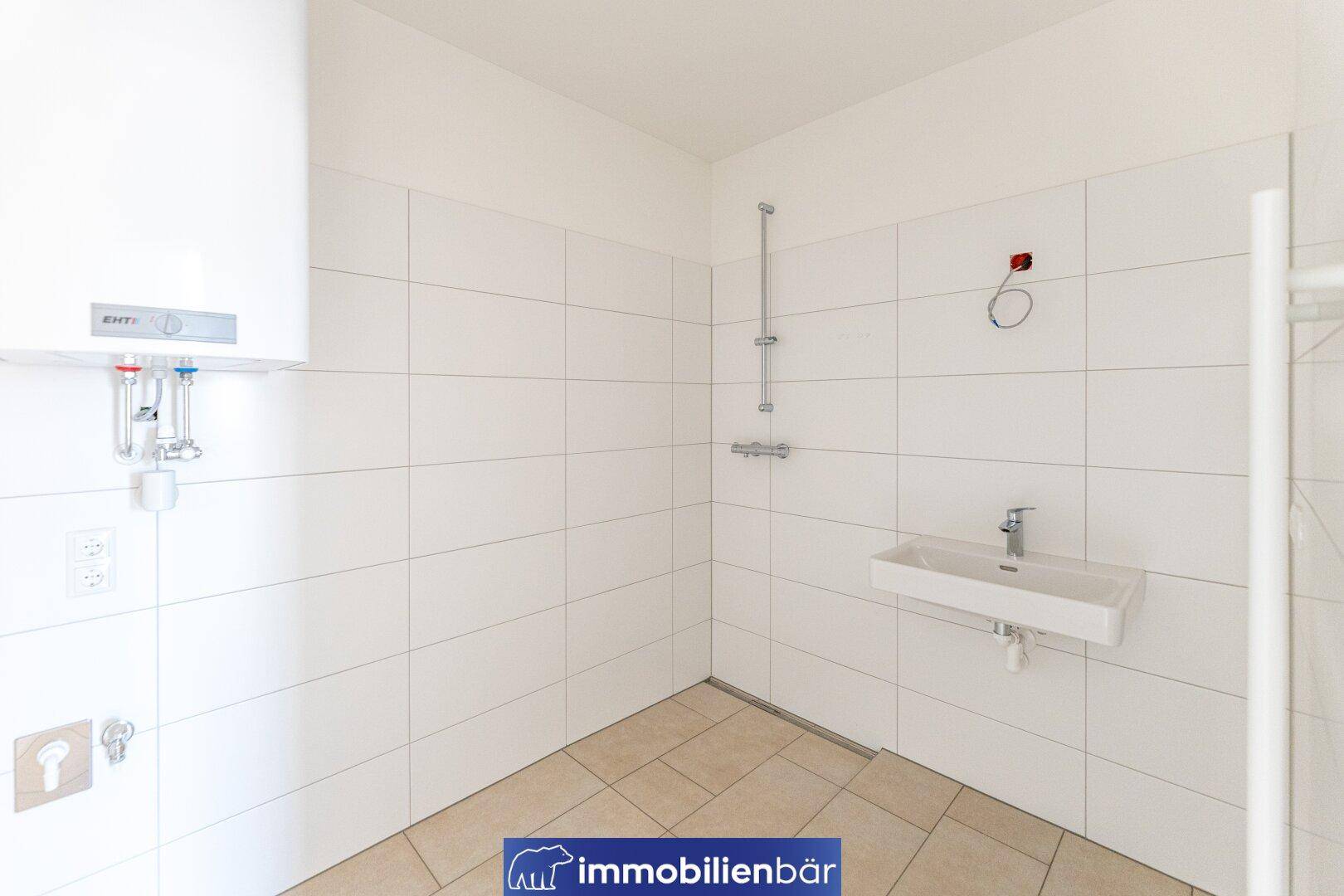 Helles Badezimmer mit Duschbereich, Waschbecken und weiß gefliesten Wänden.