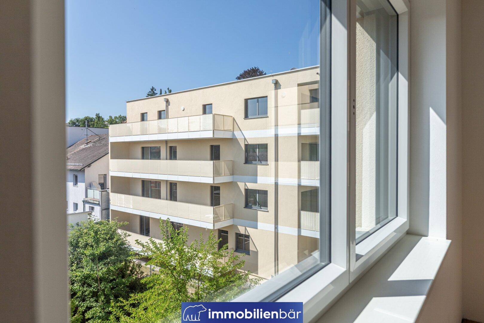 Blick aus dem Fenster auf die moderne Fassade des Wohngebäudes und die Umgebung.