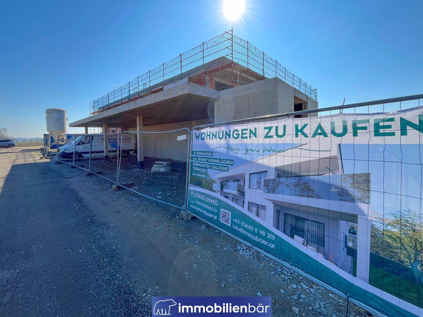 Neubau im Rohbauzustand mit Werbebanner für Wohnungen zum Verkauf.