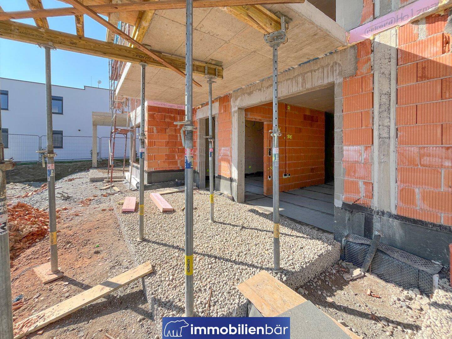 Baustelle eines Neubaus mit sichtbaren Ziegelwänden, Betonstrukturen und Baugerüst.