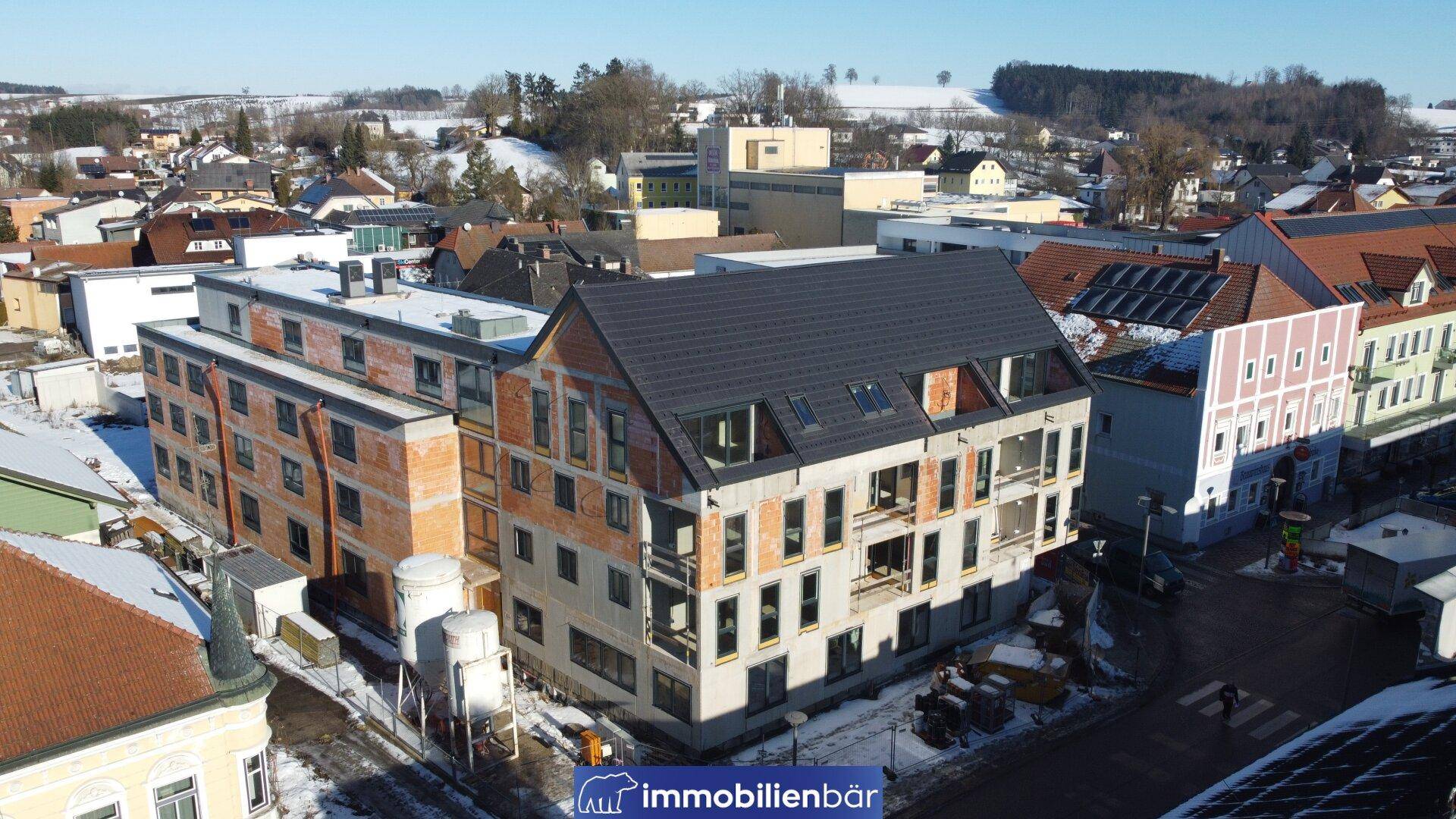 Luftaufnahme eines im Bau befindlichen Gebäudes mit Dach und Fassade in verschneiter Umgebung.