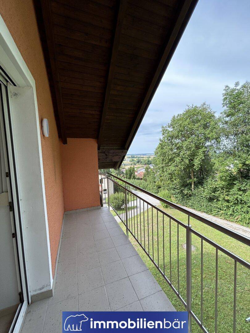 Überdachter Balkon mit Fliesenboden und weitem Blick ins Grüne und die Umgebung.