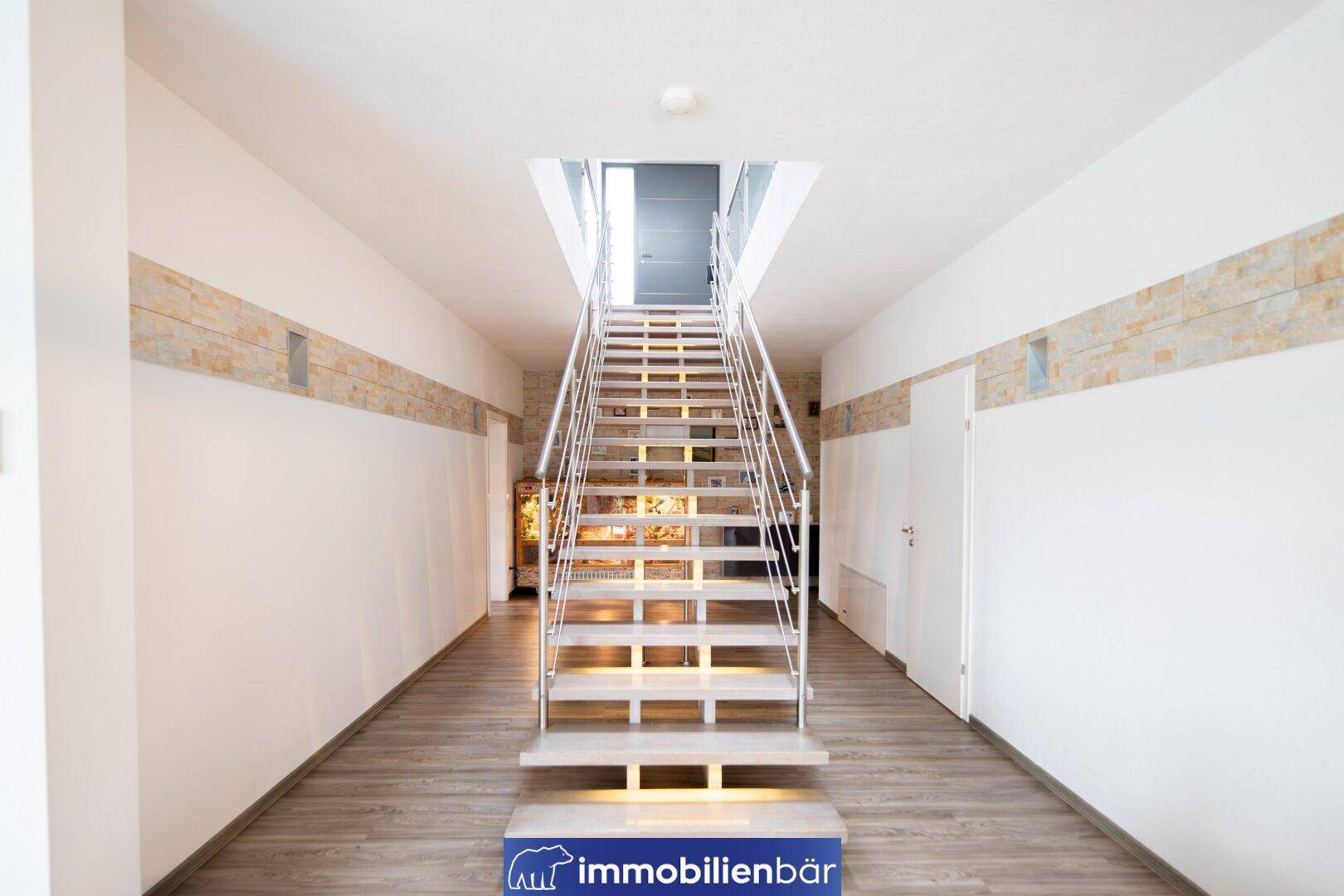 Heller Flur mit moderner Treppe und Holzstufen, die zu den oberen Etagen führt.