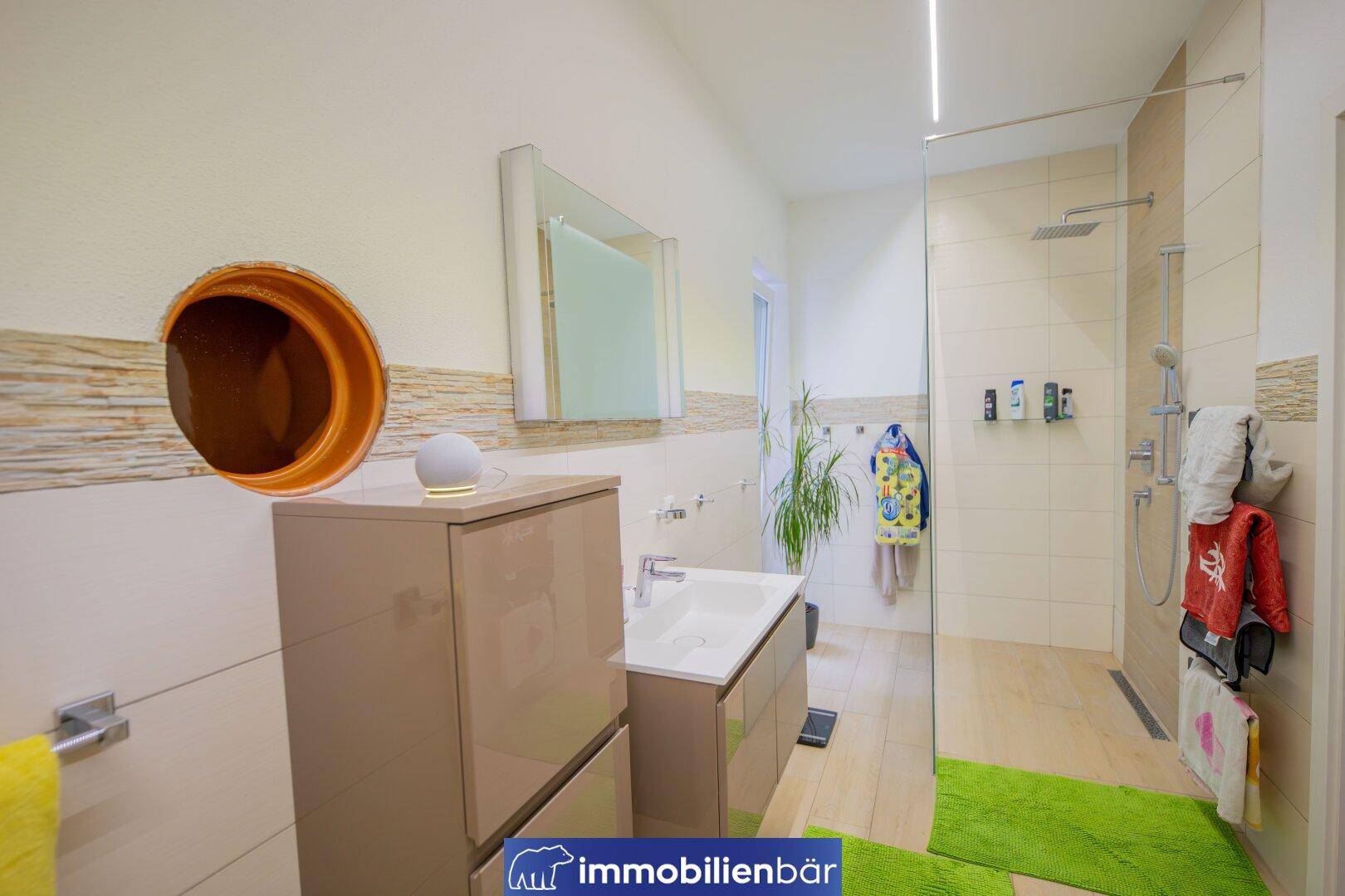 Modernes Badezimmer mit begehbarer Dusche, Einzelwaschbecken und hellen Fliesen.