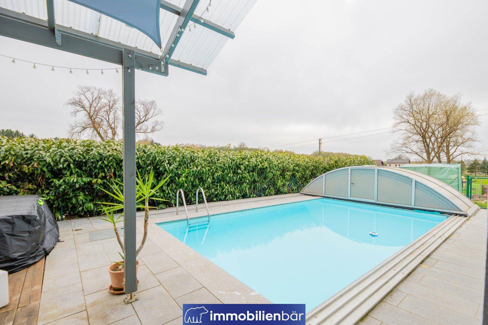 Großer Außenpool mit Abdeckung und Liegeflächen, ideal für Entspannung im Freien.