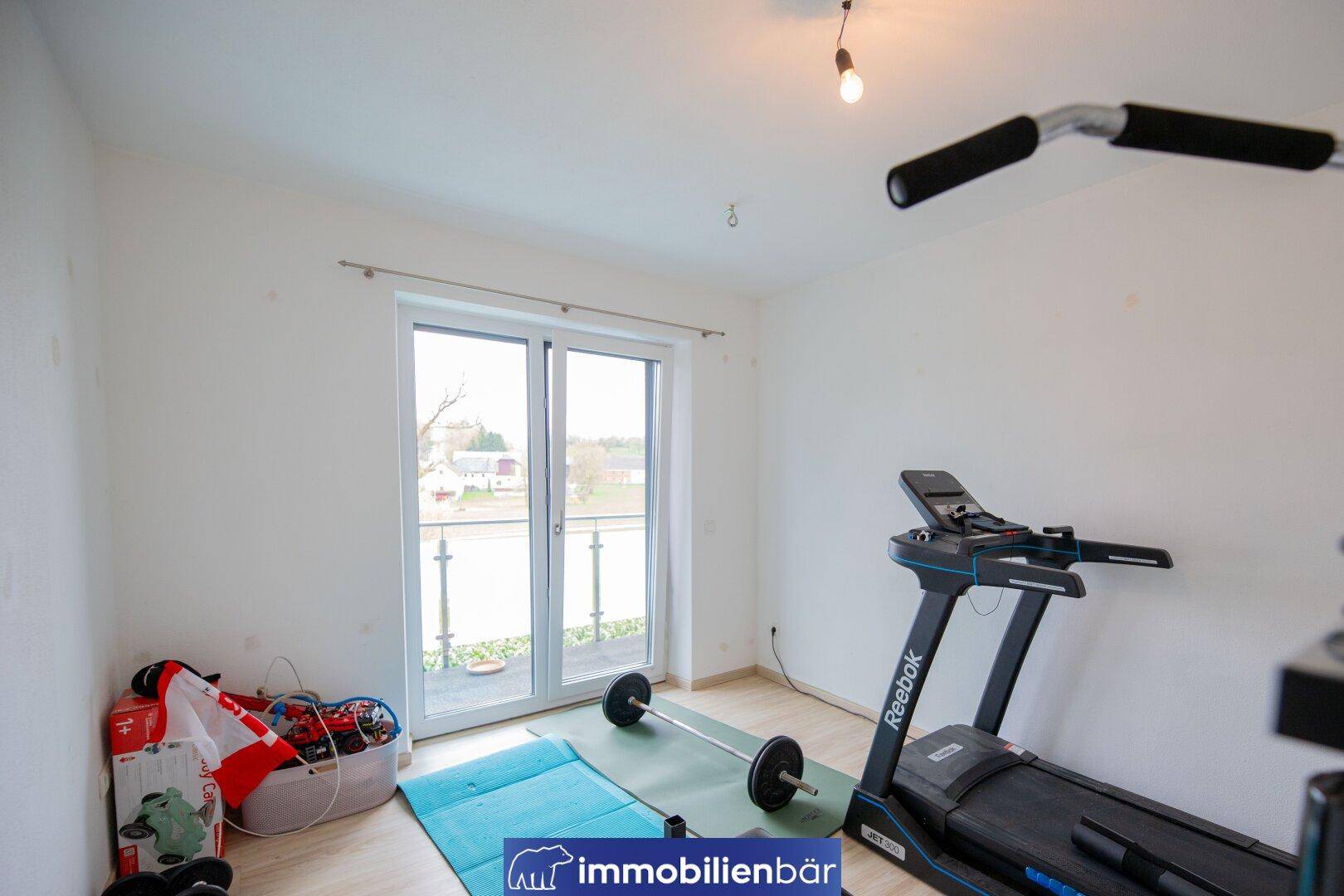 Fitnessraum mit Laufband und Hanteln, ideal für das Training zu Hause.