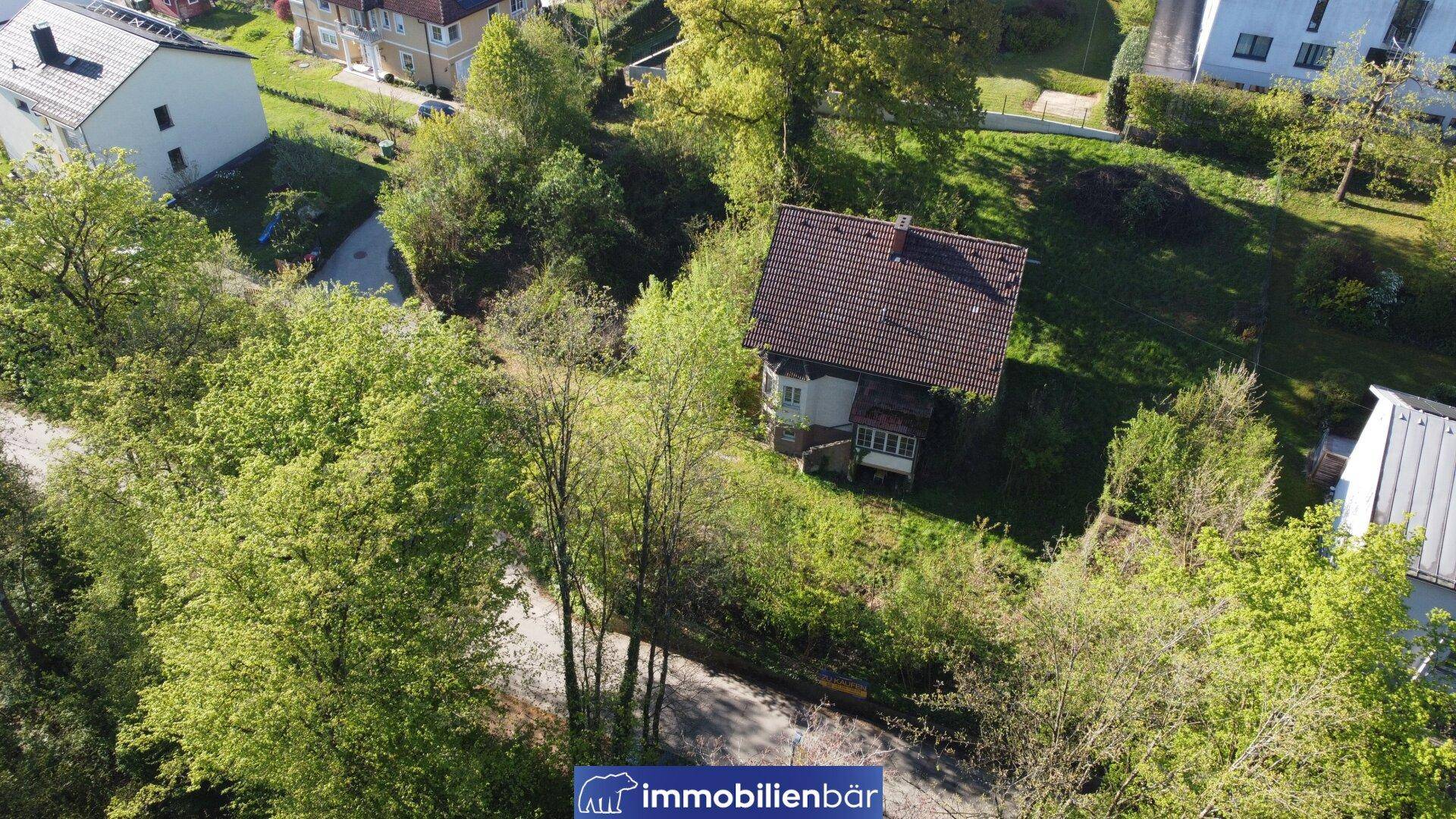 Luftbild eines Einfamilienhauses mit Satteldach, umgeben von Bäumen und Grünflächen.