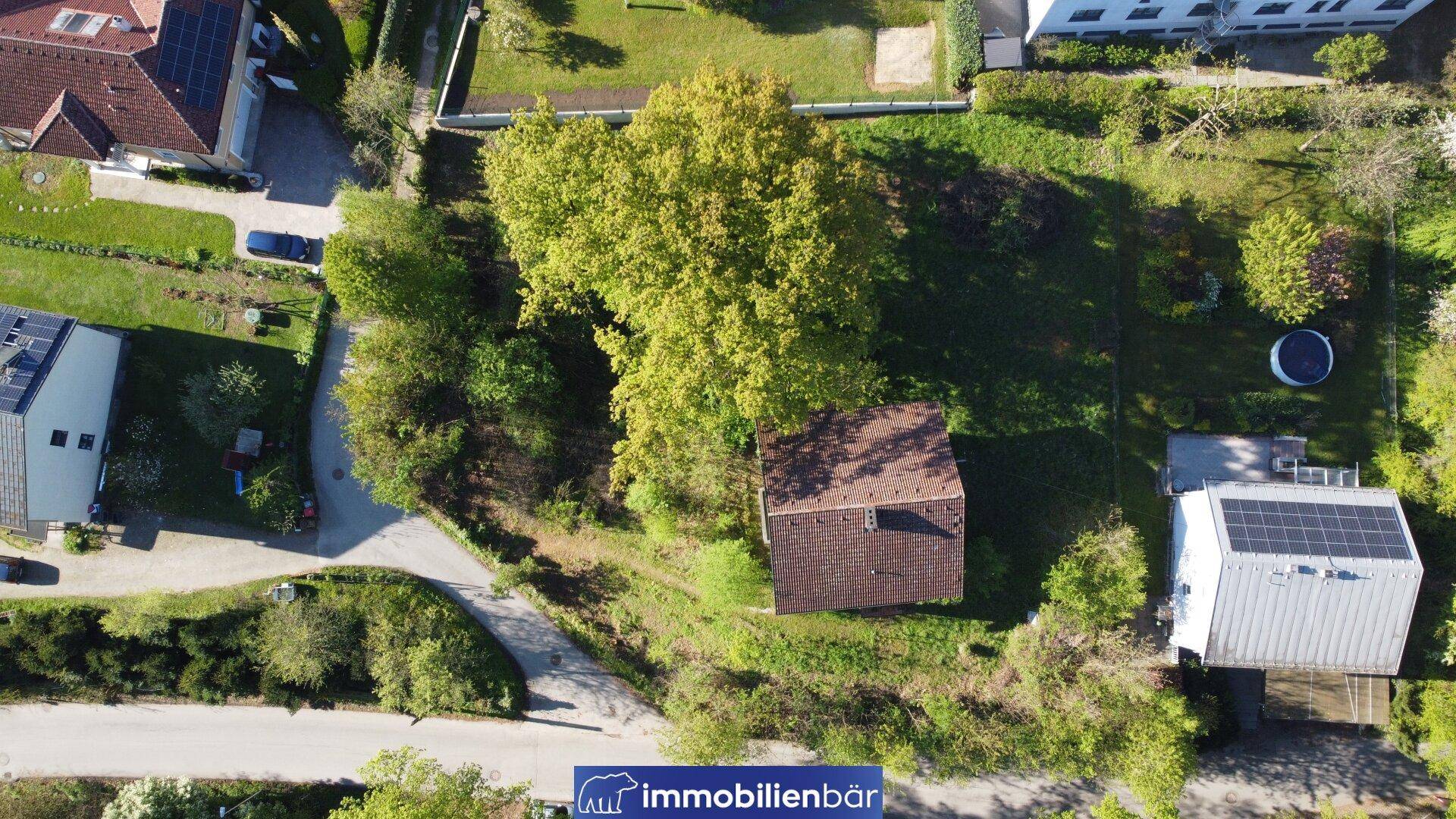 Draufsicht auf ein Wohnhaus mit großem Garten und angrenzenden Grundstücken in grüner Umgebung.