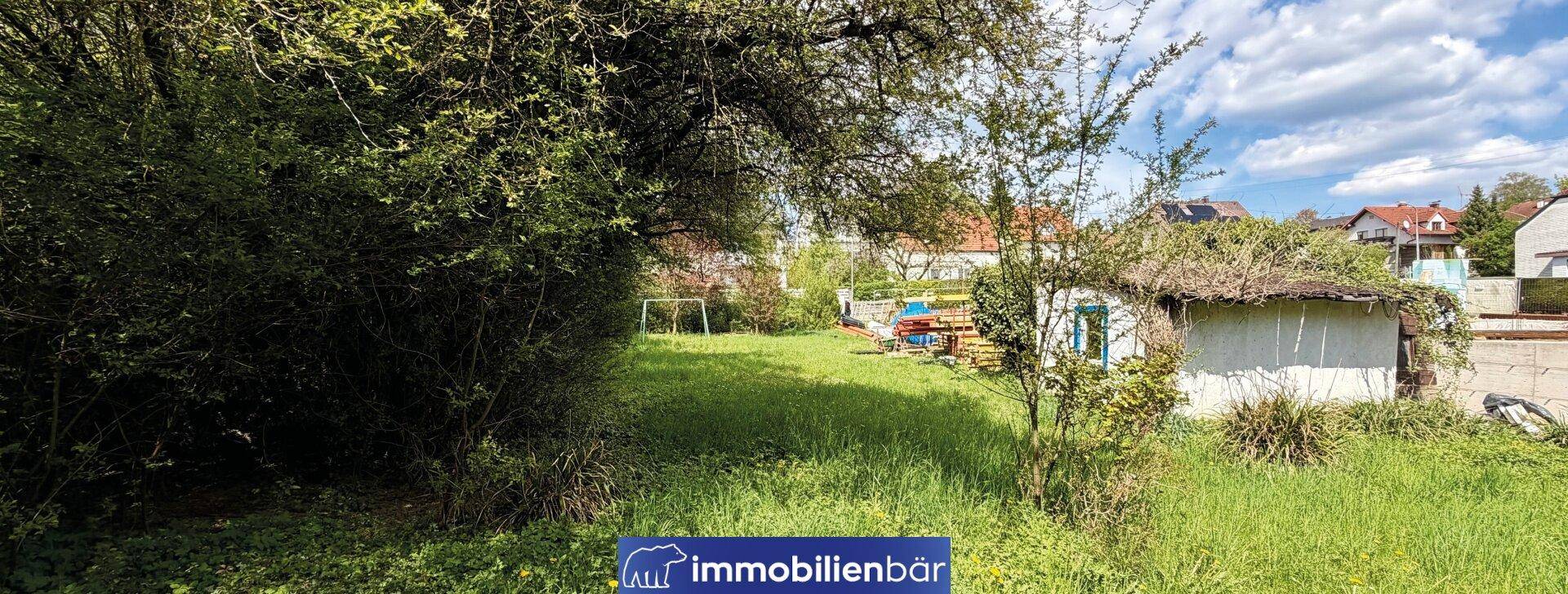 Weitläufiges grünes Grundstück mit einem kleinen Schuppen und Blick auf die Umgebung.