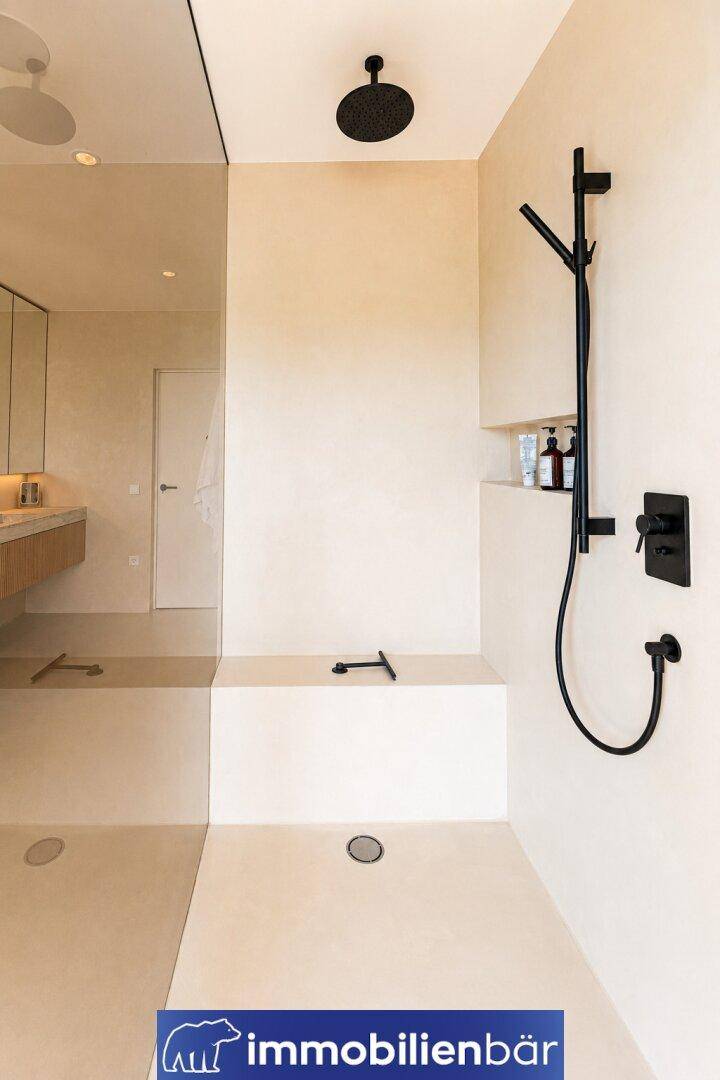 Elegante begehbare Dusche mit schwarzen Armaturen und minimalistischem Design.