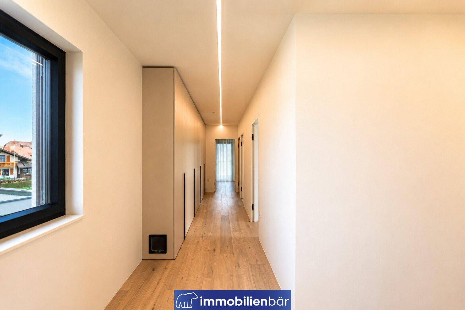 Heller Flur mit Holzboden, integrierten Schränken und einem Fenster für natürliches Licht.